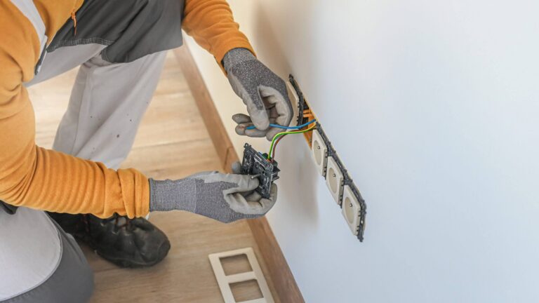 Electrical installation. An electrician's hands during installat Electrical installation. An electrician during installation a wall sockets to multi pack socket. Hands and sockets out of focus.